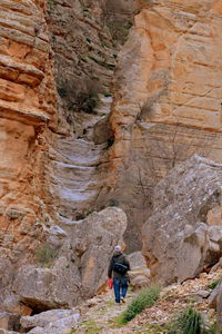 Rear view of man walking on rocky mountain