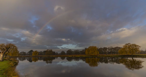 Scenic view of rainbow over lake against sky