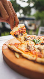 Close-up of hand holding pizza