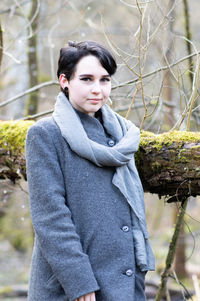 Portrait of young woman standing in park during winter