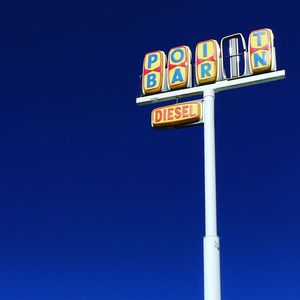 Low angle view of road sign against clear blue sky