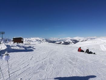 People on snowcapped mountain against clear blue sky