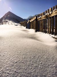 Wooden fence on snowcapped mountain against sky