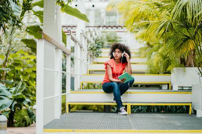 Full length portrait of woman sitting against building