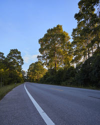 Empty road amidst trees against clear sky