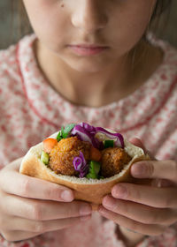 Cropped image of girl eating falafel wrap sandwich