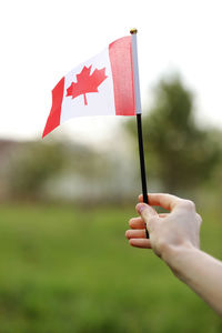 Flag of canada, national symbol waving against, sunny day. canada flag in woman hand.