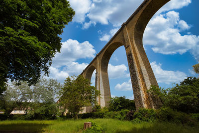 Low angle view of arch bridge against cloudy sky