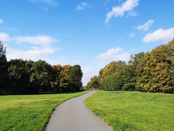 Empty road amidst trees against sky