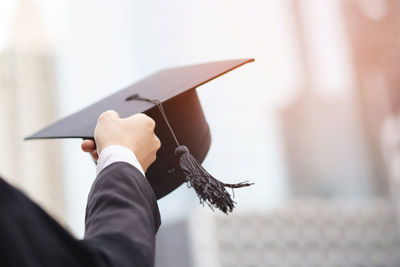 Cropped hand of person holding mortarboard