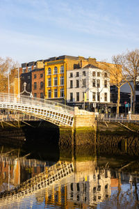 Bridge over river by buildings against sky in city