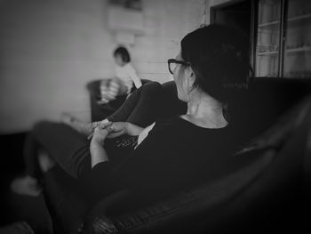 Woman holding cigarette while sitting on sofa at home