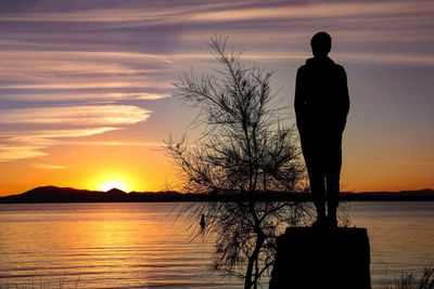 Silhouette man standing by sea against sky during sunset