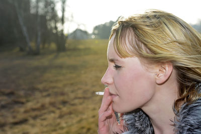 Profile view of woman smoking cigarette on field