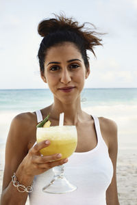 Smiling young with cocktail on beach