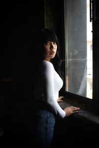 Side view of woman looking through window