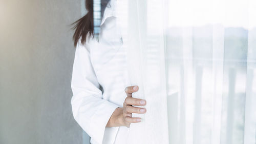 Midsection of woman standing by curtain