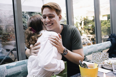 Happy man embracing sister at restaurant