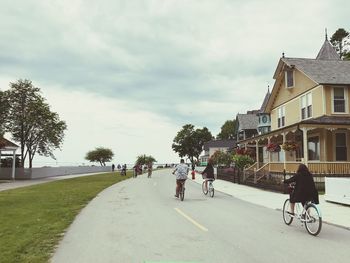 People riding bicycle on road against sky