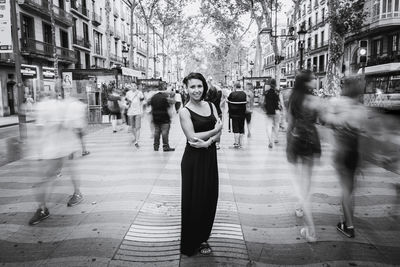 Portrait of young woman with people walking in city