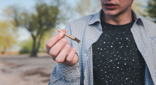 Midsection of man smoking marijuana joint in city