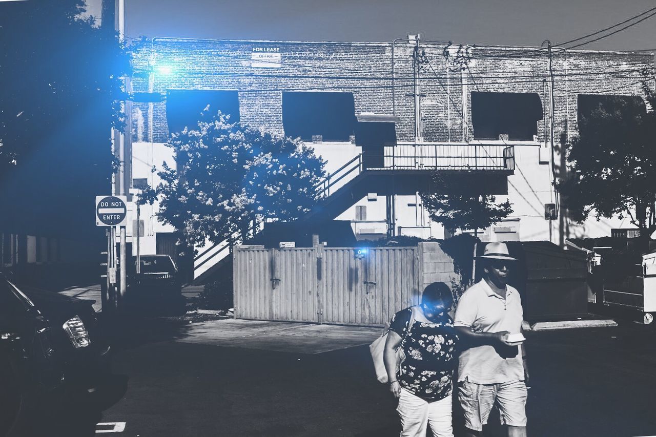 REAR VIEW OF PEOPLE WALKING ON ILLUMINATED BUILDINGS IN CITY