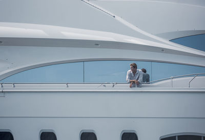 Man looking away while leaning on railing of ship