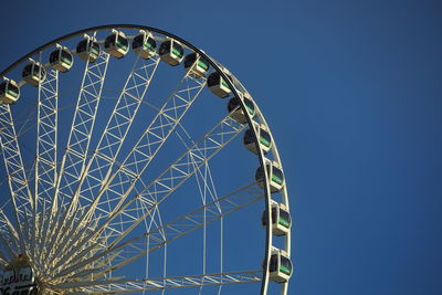 Low angle view of ferris wheel against blue sky