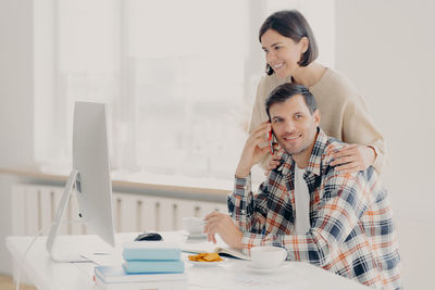 Woman looking computer while man talking on phone