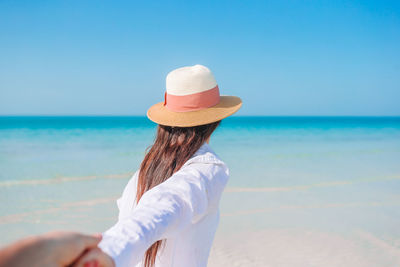 Rear view of woman holding hand at beach