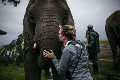Blond young woman kissing elephant at zoo