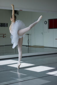 Classical dancer in white tutu dancing in ballet studio