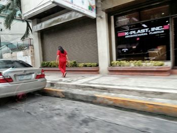 Full length of man walking on footpath in city