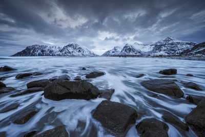 Scenic view of sea and snowcapped mountains against sky