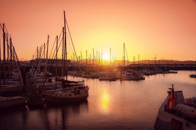 Boats moored at harbor during sunset