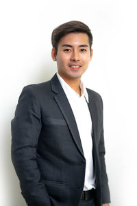 Portrait of young man standing against white background