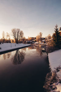 Scenic view of buildings by canal against sky during winter
