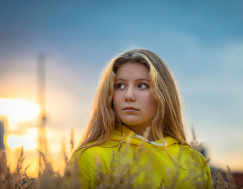 A young girl with long hair walks across a field with tall grass. blonde hair.
