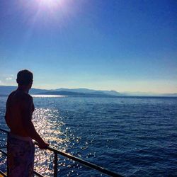 Rear view of man standing against sea