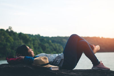 Man lying down while sitting on land against sky