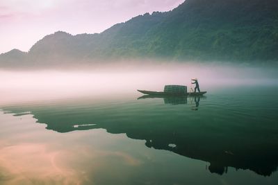 Man sailing boat in sea during foggy weather