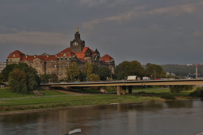 Bridge over river by buildings against sky