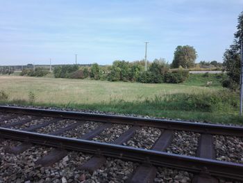 Railroad track amidst field against sky