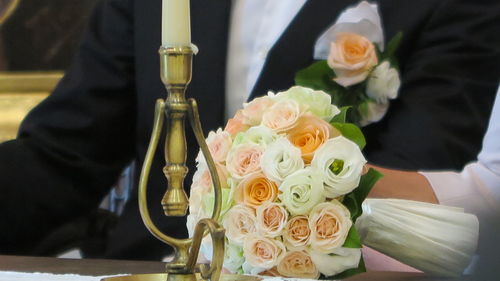 Cropped hand of bride holding bouquet with bridegroom at wedding ceremony