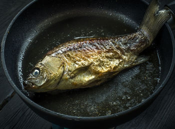 High angle view of fish in cooking pan on wooden table