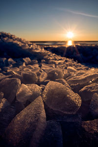 Close-up of frozen sea against sky during sunset