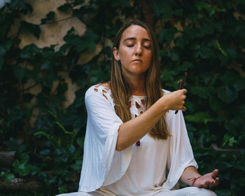 Close-up of young woman meditating while sitting outdoors