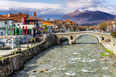 Arch bridge over river amidst buildings in town