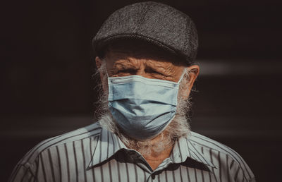 Portrait of man wearing mask against black background