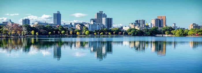 Reflection of buildings in lake against sky in city